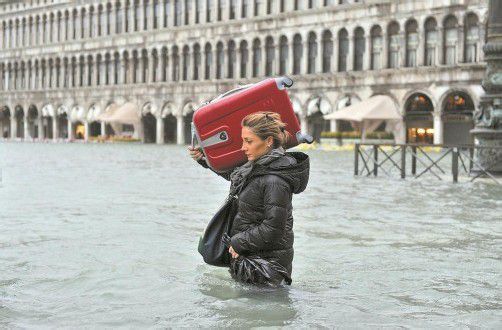 Diese Touristin kämpfte sich gestern durch das Hochwasser am Markusplatz in Venedig. Foto: DAPD