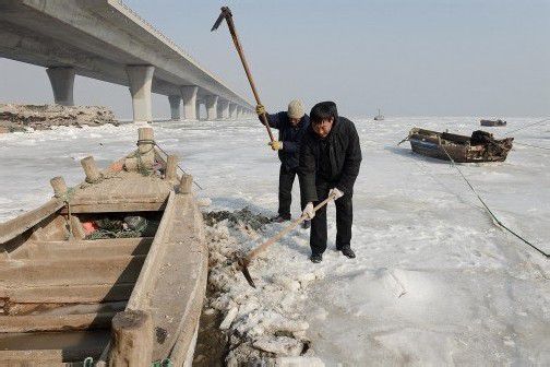 Diese Fischer aus der ostchinesischen Stadt Jiaozhou versuchen ihr in der Meeresbucht eingefrorenes Boot freizuhacken. Foto: AP