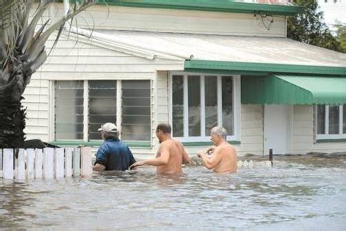 Diese drei Männer in Bundaberg versuchen, einige Habseligkeiten aus dem überschwemmten Haus zu retten. Foto: EPA