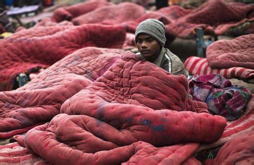 Mit Decken versucht sich dieser Mann in Neu-Delhi zu wärmen.