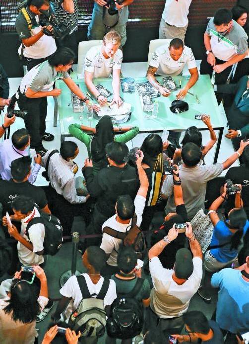 Das ist noch die leichteste Übung im heißen Sepang: Nico Rosberg und Lewis Hamilton schreiben Autogramme. Foto: ap