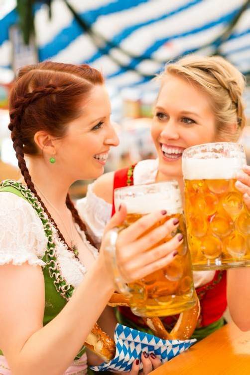 Young women in traditional Bavarian clothes - dirndl or tracht - on a festival or Oktoberfest in a beer tent