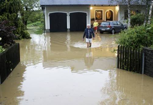 Bewohner in ihrem überfluteten Hof in Pachern nach den starken Regenfällen. Zahlreiche Garagen und Keller wurden überflutet. Foto: APA