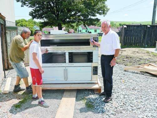 Oberhauser (r.) mit zwei rumänischen Arbeitern und dem Backofen. Ab September soll er seinen Dienst tun. Foto: Entner