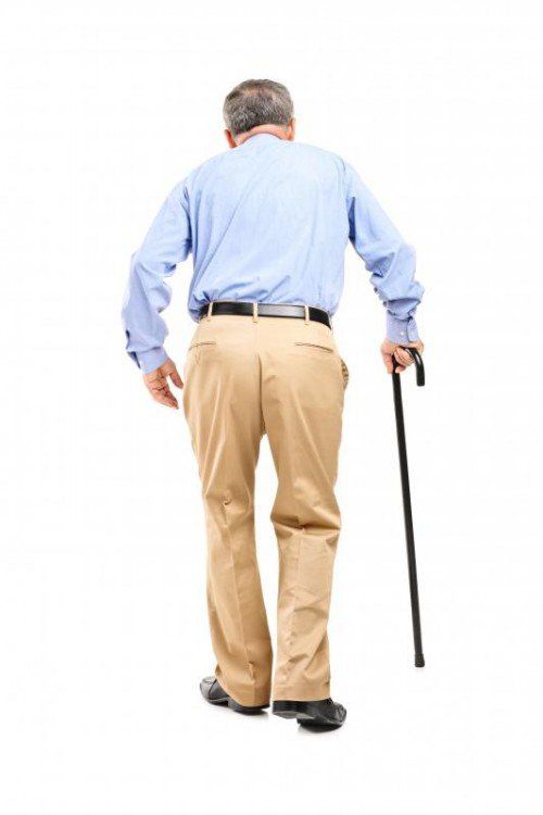 Full length portrait of a senior man with cane walking isolated on white background