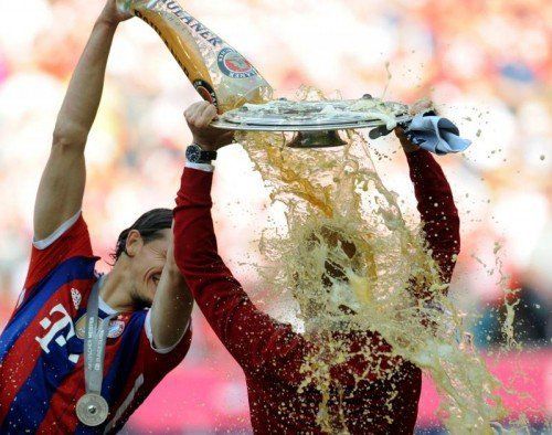 Daniel van Buyten (l.) verabreicht Bayern-Coach Pep Guardiola die traditionelle Bierdusche. Foto: epa