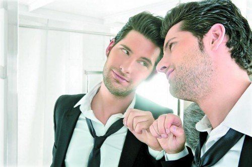 Handsome narcissistic suit proud young man looking himself in the mirror