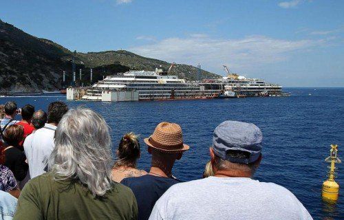 Die „Costa Concordia“ soll nun zum Abwracken abtransportiert werden. Touristen verfolgen die letzten Vorbereitungen. Foto: AP
