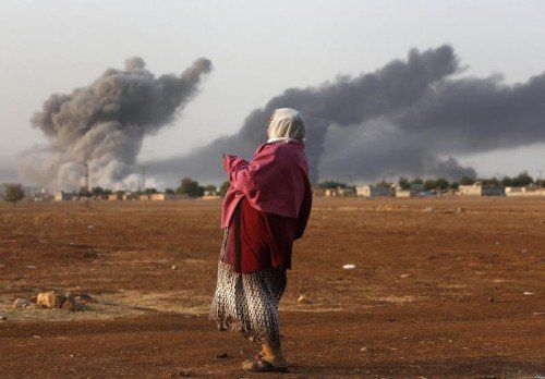 Bomben der Anti-IS-Allianz fallen auf Kobane. Eine Kurdin sieht von der syrisch-türkischen Grenze aus zu. AP