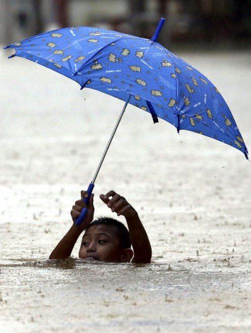 Dieser Bub kämpft sich in Malaysia durch die Wassermassen.  Foto: EPA