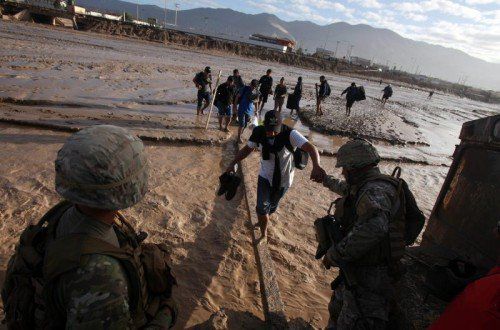 Chilenische Soldaten helfen den Bewohnern der Ortschaft Charañal über einen Fluss, der sich durch die schweren Unwetter gebildet hat. Foto: EPA