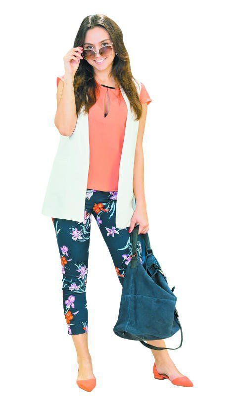 Riccarda in einem Frühlingsoutfit von Magno: Schuhe und Hose (39,99), oranges Shirt (29,99), Weste (49,99), Sonnenbrille (19,99) und Handtasche (49,99).