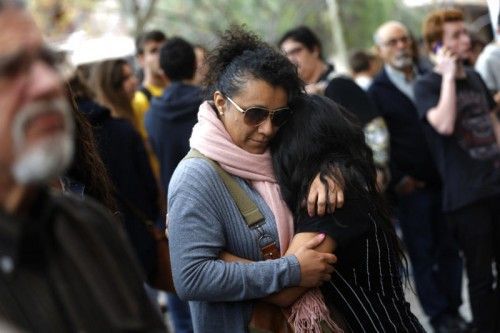 Menschen trösten einander vor der betroffenen Schule. Über das Motiv des 13-Jährigen herrscht noch Unklarheit. Foto: AP