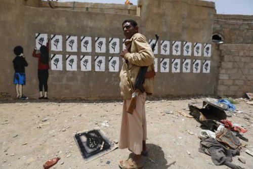Ein jemenitischer Huthi-Milizionär vor einer Graffiti-Wand in Sanaa, die an die vielen Opfer der saudischen Luftschläge erinnern soll.  FOTO: EPA