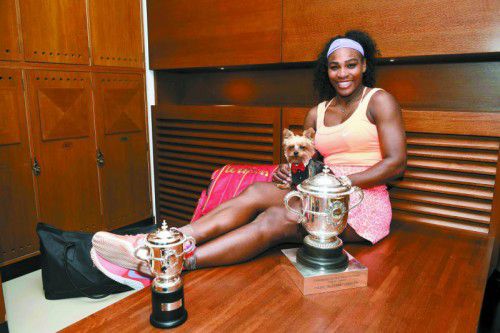 in Wimbledon wartet die nächste Trophäe: Serena Williams zwischen Hund Chip und ihren Pokalen von Paris. Foto: Reuters