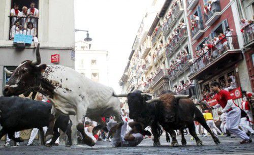 Die Stiere haben einen Mann zu Boden gerissen. Zahlreiche Menschen beobachten das Spektakel von ihren Balkonen aus. Foto: Reuters