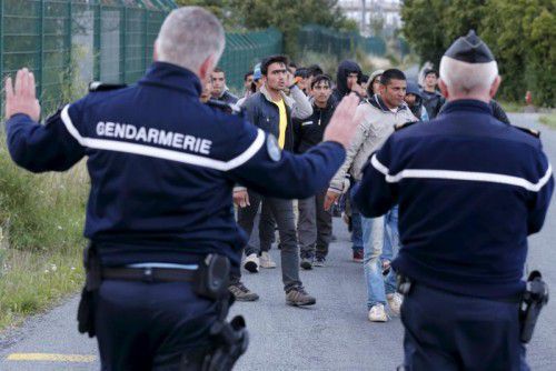 Gendarmeriebeamte versuchen Migranten daran zu hindern, zum Eurotunneleingang zu gelangen.