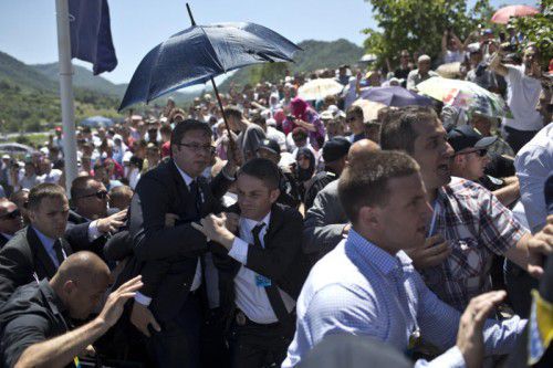 Mit Schirmen versuchen Bodyguards den Serbischen Premier Aleksandar Vucic vor fliegenden Steinen und Flaschen zu schützen. AP