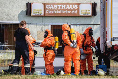 Feuerwehrmänner ziehen sich Schutzanzüge an. Es besteht Explosions­gefahr an der Absturzstelle.