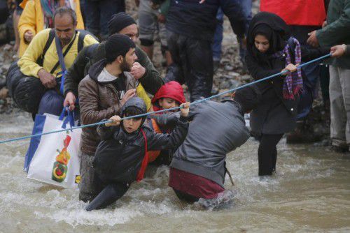 Flüchtlinge kämpfen sich durch einen Fluss nahe der griechisch-mazedonischen Grenze.