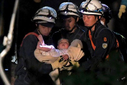 Feuerwehrleute retten ein Baby aus einem eingestürzten Haus in der vom Erdbeben betroffenen Stadt Mashiki.