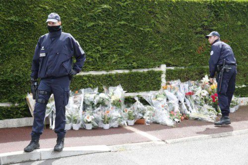 Polizisten legen vor dem Haus des getöteten Ehepaars in Magnanville Blumen nieder.