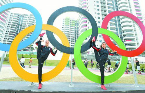 Die Duett-Synchronschwimmerinnen Anna Maria Alexandri und Eirini Maria Alexandri turnen sich an den Olympiaringen im Olympischen Dorf fit.