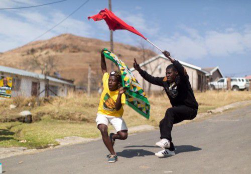 Ein Anhänger des ANC und einer der SACP (Communist Party) tanzen auf der Straße im Wembezi-Township bei Durban.
