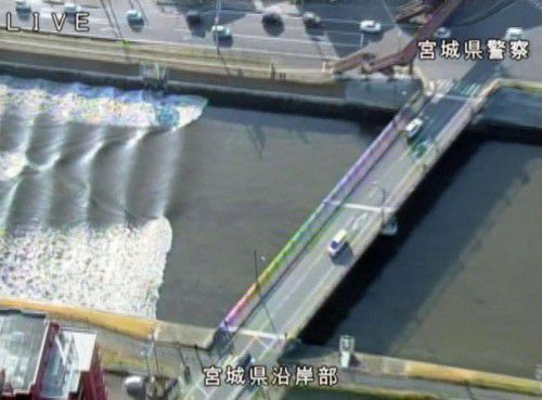 Die kleine, aber sichtbare Tsunamiwelle rollt den Fluss Sunaoshi hinauf, wie Fernsehbilder aus dem Helikopter zeigen. Foto: Reuters