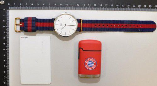 Wer kennt diese Gegenstände? Ein Feuerzeug mit FC-Bayern-Logo, eine Uhr der Marke Daniel Wellington und eine weiße Zugangskarte.