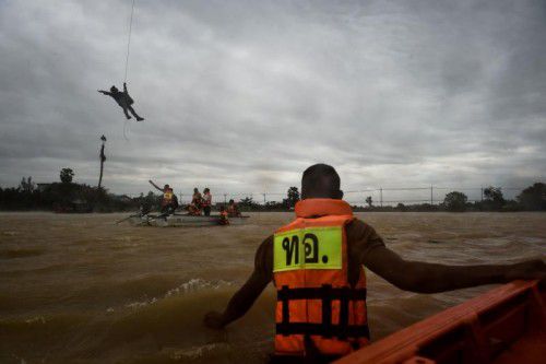 Ein Soldat seilt sich aus einem Helikopter ab, um ein Rettungsboot zu unterstützen.  Foto: AFP