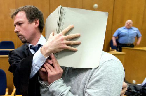 Ein Angeklagter verdeckt mit Hilfe seines Verteidigers im Gerichtssaal sein Gesicht. Foto: DPA