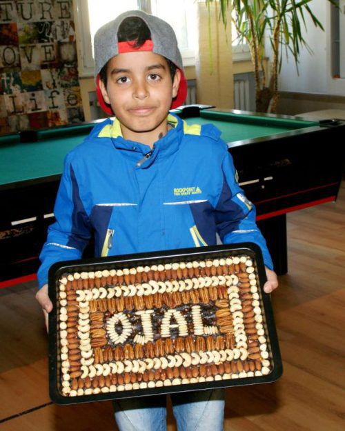 Ali (10) mit der syrischen Nachspeisen-Spezialität Tmreya.