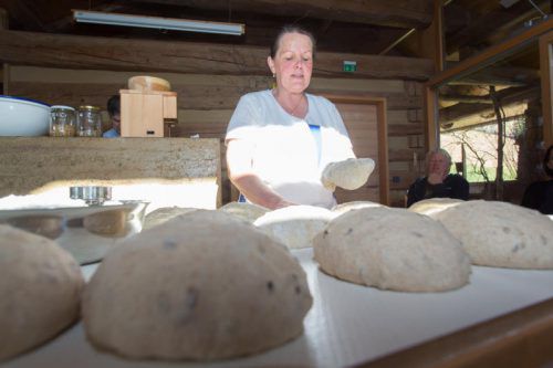 Die Bäuerin zeigt den Teilnehmern, wie man selbst Brot herstellt.