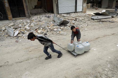 Zwei Kinder beim Wasserschleppen neben den Trümmern in der syrischen Stadt Aleppo. Foto: AFP