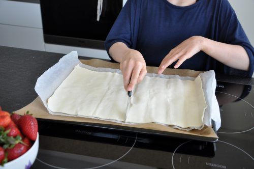 Den Blätterteig auf einem mit Backpapier belegten Backblech entrollen und halbieren.