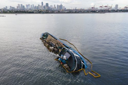 Es wurden Ölsperren rund um das auf der Seite liegende Frachtschiff errichtet.  AP