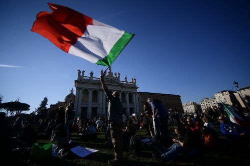 Ein Mann schwenkt auf der Piazza San Giovanni in Rom die italienische Flagge während einer Demonstration gegen den „Super Green Pass". AFP