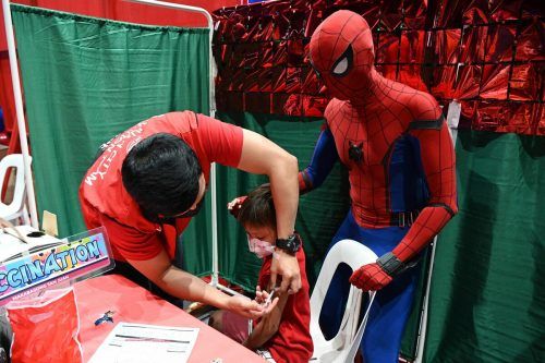 Ein Spiderman-Darsteller spricht einem Kind, das im philippinischen Manila gegen Corona geimpft wird, Mut zu. AFP