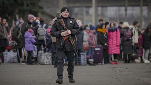 Ein ukrainischer Polizist mit einem Sturmgewehr patroulliert entlang eines Bahnsteigs, an dem Menschen aus der Ostukraine auf einen Zug nach Kiew warten.