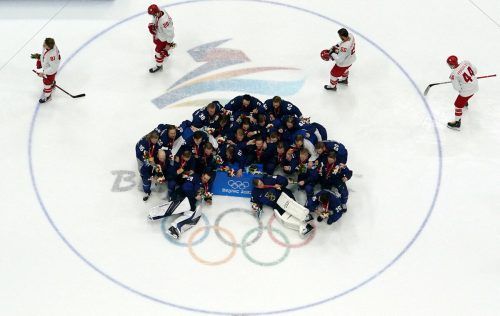 Symbolbild des Olympischen Finales im Eishockey: Finnland jubelt und im Hintergrund schleichen die Russen vom Eis. reuters