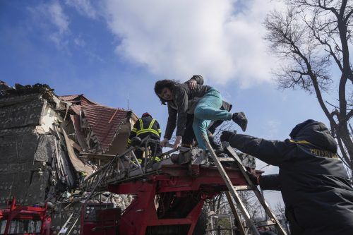 Feuerwehrleute helfen einer Frau aus einem zerstörten Gebäude in Mariupol. AP