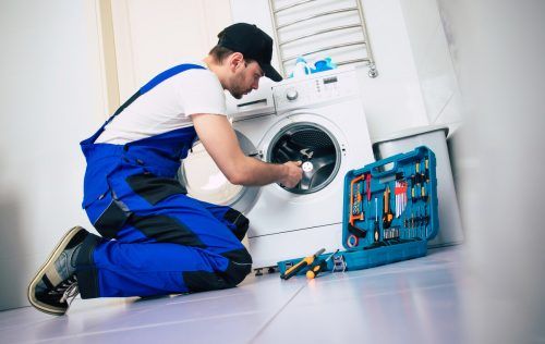Der Elektriker repariert die Waschmaschine im Badezimmer.  shutterstock