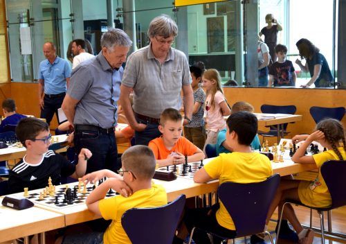 Konzentriert widmen sich die Schüler ihrem Schachspiel, während die Lehrer neugierig ihre Züge verfolgen.  sco