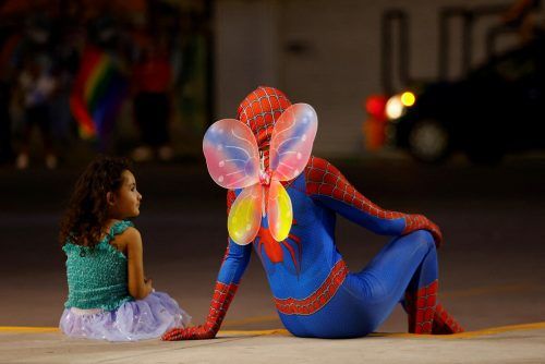 Die vierjährige Genesis spricht bei einer Pride-Parade in Ciudad Juarez mit einer Person im Spiderman-Kostüm und Schmetterlingsflügeln. RTS