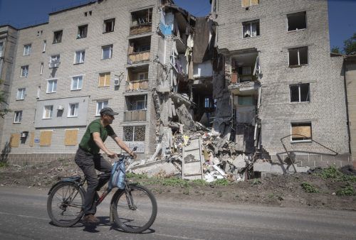 Ein Mann fährt mit dem Fahhrad in Bakhmut in der östlichen Region Donezk an einem zerstörten Gebäude vorbei.  AP