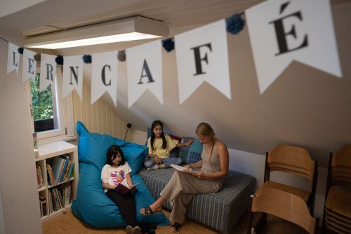 Freiwillige Mitarbeiterinnen und Mitarbeiter unterstützen Kinder im Lerncafé. caritas