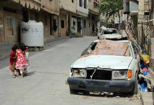 Im Bürgerkriegsland Jemen, in der Stadt Taiz, laufen Kinder an einem zerschossenen Fahrzeug vorbei. AFP