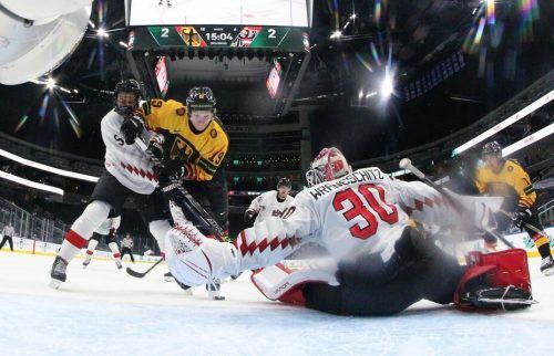 David Reinbacher und Torhüter Sebastian Wraneschitz versuchen den deutschen Stürmer Haakon Hänelt zu stoppen. IIHF