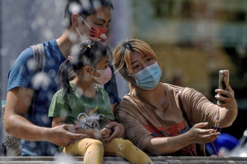 Masken-Selfie: Eine Familie fotografiert sich bei einem Einkaufszentrum in der chinesischen Hauptstadt Peking mit dem Smartphone. AFP
